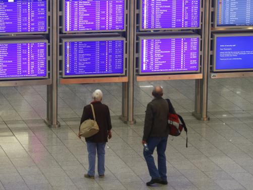 Passengers look at flight information displays during a strike at Frankfurt airport