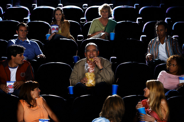 Mature Man Eating Potato Chips in Movie Theater Auditorium