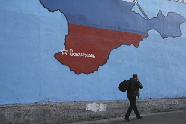 A man passes a mural showing a map of Crimea in Russian national colors on a street in Moscow