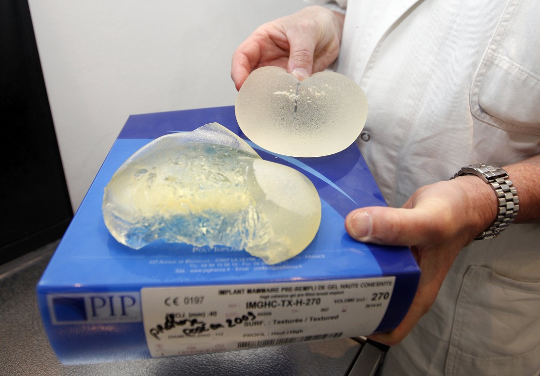 Plastic surgeon Denis Boucq poses holding defective silicone gel breast implants at his office in a clinic in Nice