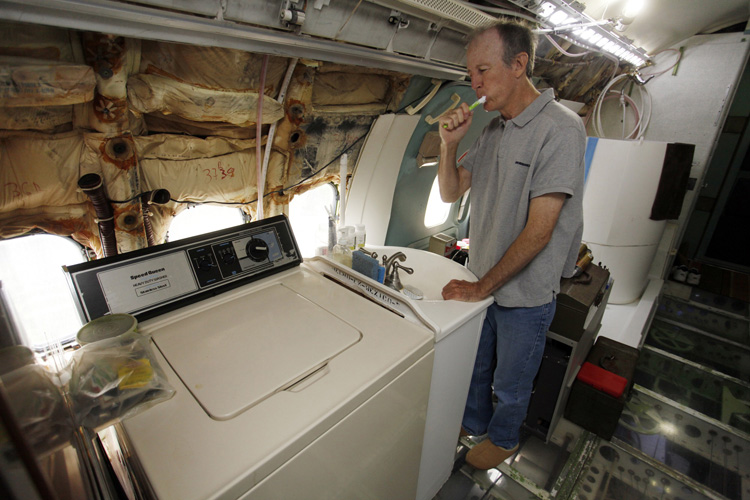 Bruce Campbell brushes his teeth at a sink in his Boeing 727 home in the woods outside the suburbs of Portland, Oregon